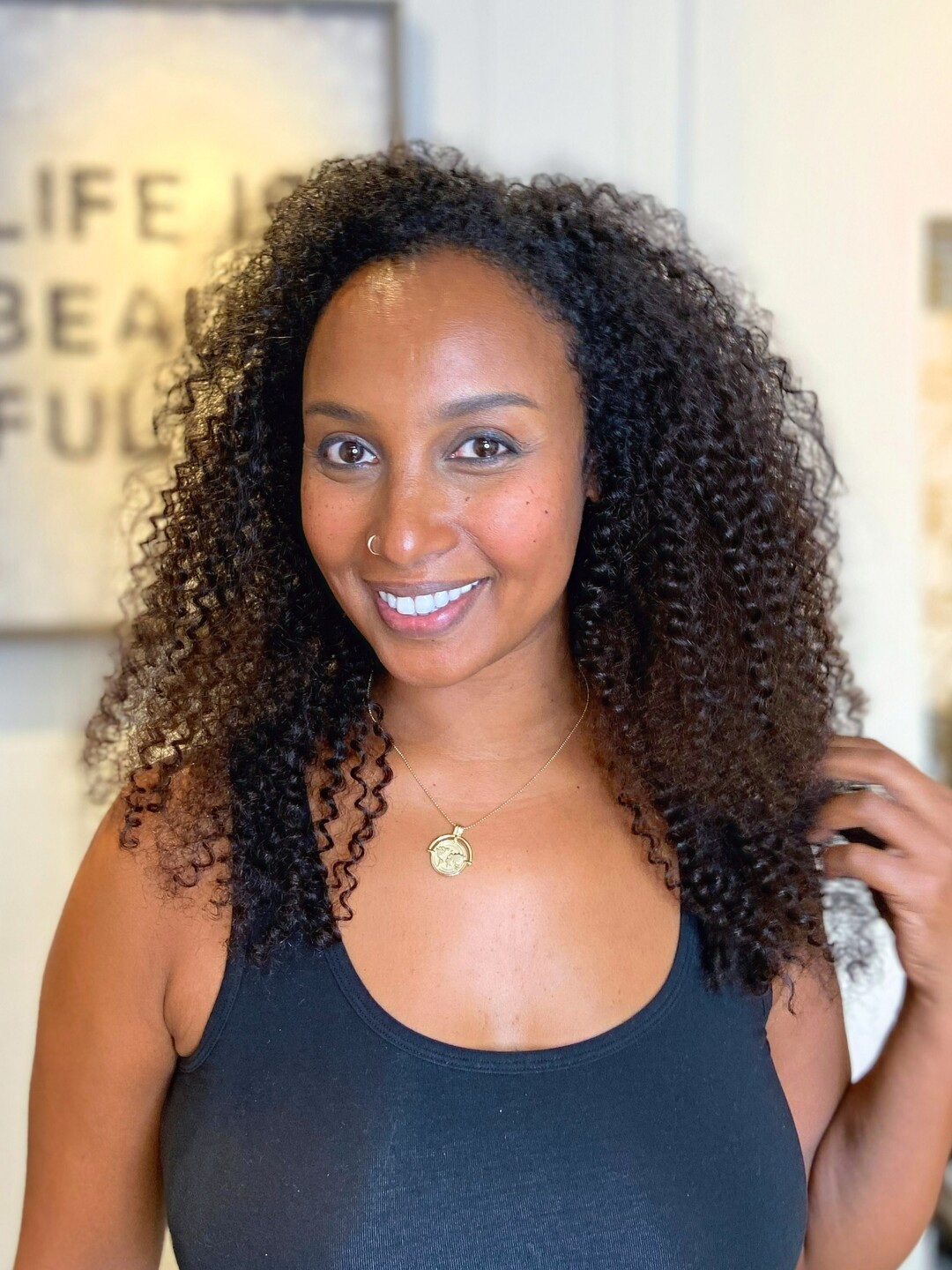 Shoulder-length dark curls on a MILVALI client, face-on, in the salon