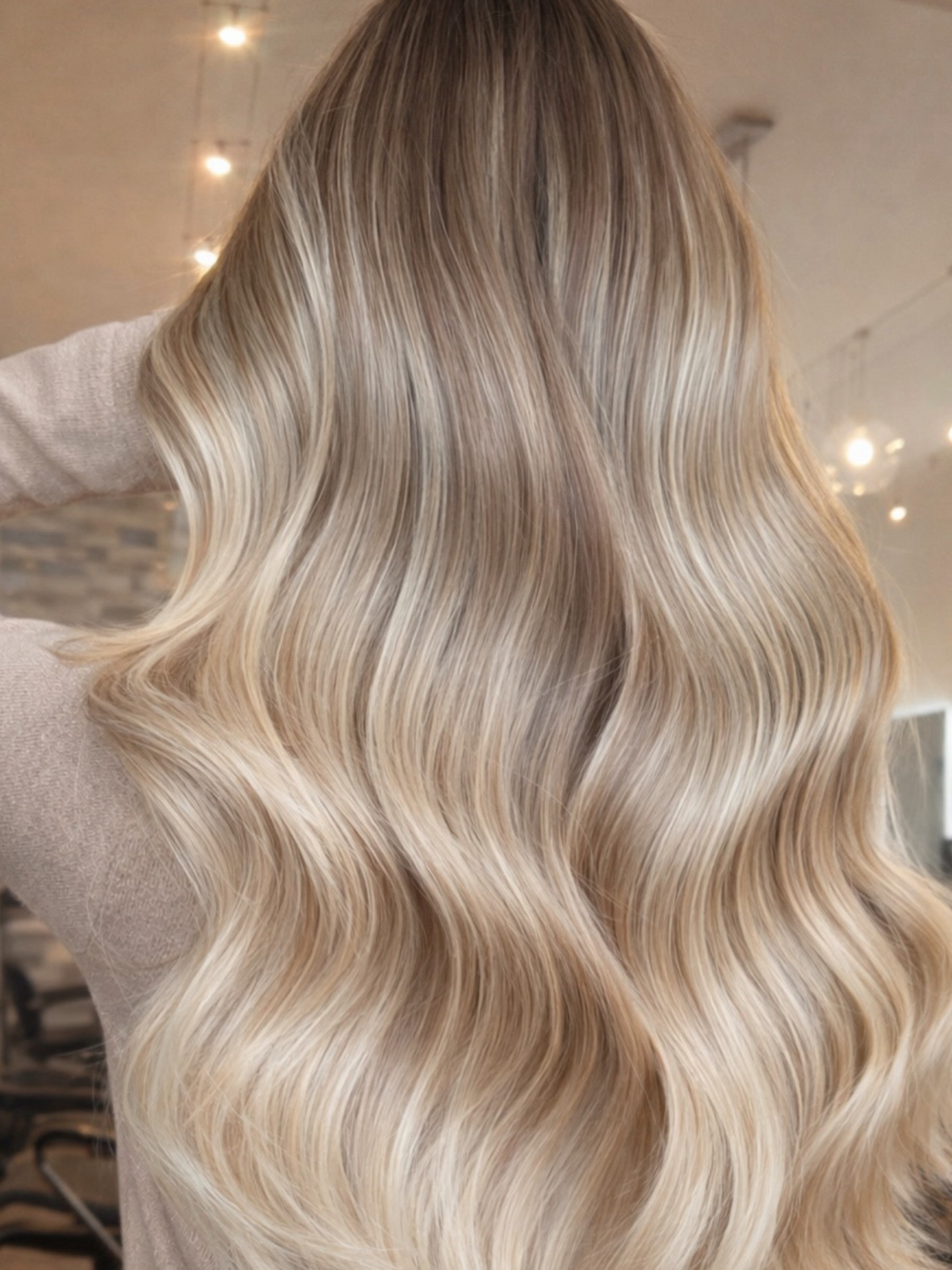 Long blonde waves with darker roots, seen from behind