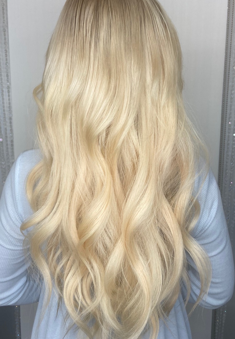 Long platinum blonde waves worn down the back, over a pale blue jumper